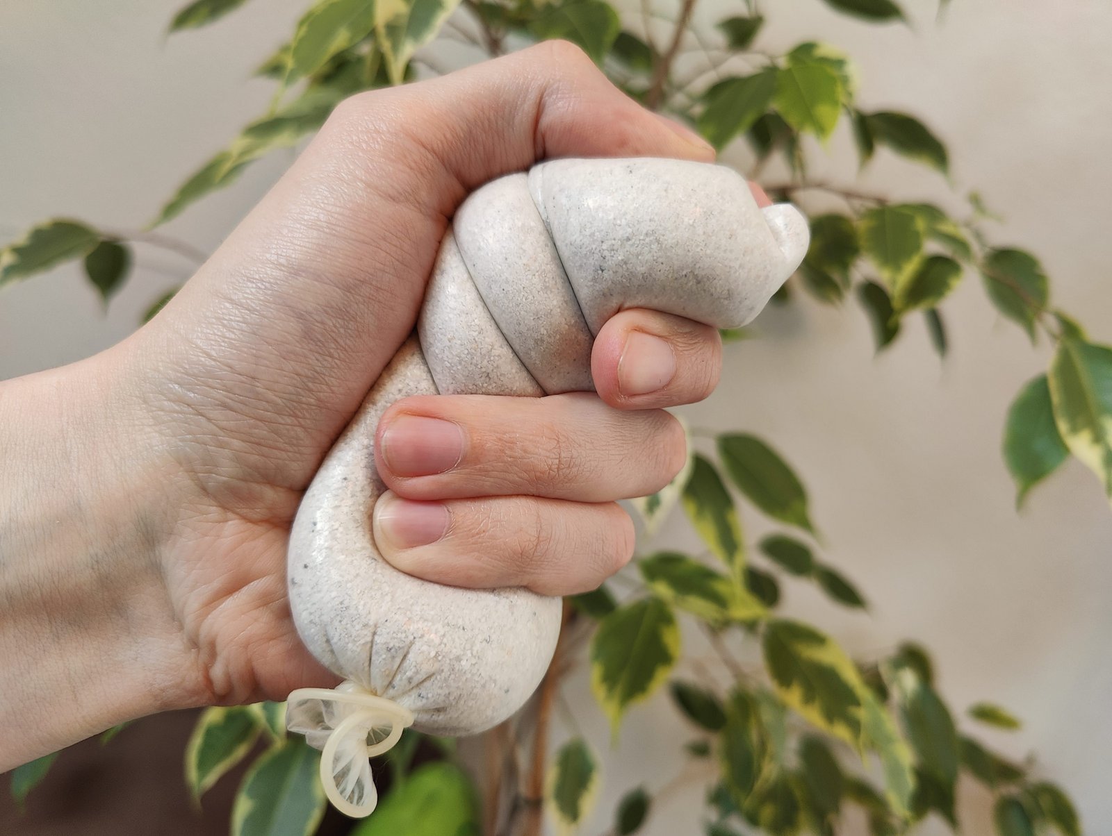 Un préservatif périmé rempli de sable, dans la main de quelqu'un qui l'utilise comme balle anti-stress